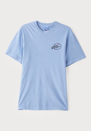 Light blue short-sleeve T-shirt made of cotton, featuring a small black logo with colorful dots on the left chest area. Classic crew neck design.