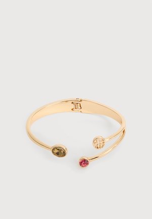 Χρυσό ανοιχτό βραχιόλι με δύο πολύχρωμους λίθους, έναν καφέ και έναν ροζ, και ένα κυκλικό χρυσό έμβλημα σε μία άκρη.