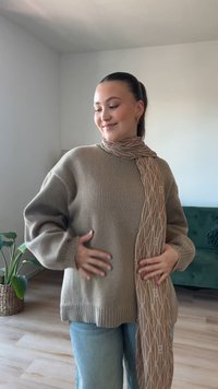 Beige kötött pulóver laza fazonnal, bordás szegéllyel. Párosítva egy mintás világosbarna sállal, amely geometrikus mintázattal rendelkezik. Hétköznapi kék farmernadrág.