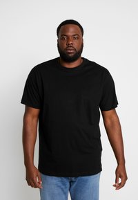 T-shirt en coton noir à manches courtes, encolure ras du cou et coupe décontractée. Porté avec un jean en denim bleu. Design simple, couleur unie.