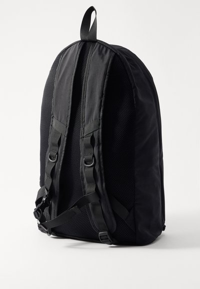 Sac à dos noir avec un dos en maille texturée, des bretelles réglables, une boucle supérieure pour le suspendre et un design moderne et épuré.