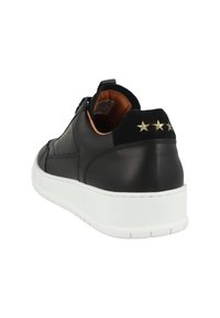 Fekete bőr sportcipő fehér talppal, fekete velúr sarokkal, és három arany csillag díszítőelemmel a hátsó részen. Simaság és alacsony profil jellemzi.