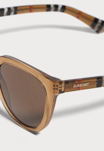 Кафяви слънчеви очила Burberry с тъмни стъкла, прозрачни рамки и райе по дръжките, показани на бял фон.
