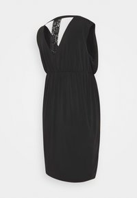 Černé šaty s výstřihem do V a průstřihem na zádech. Obsahují texturovanou krajkovou vsadku, elastický pas a krátké rukávy. Hladká tkanina, design do délky ke kolenům.