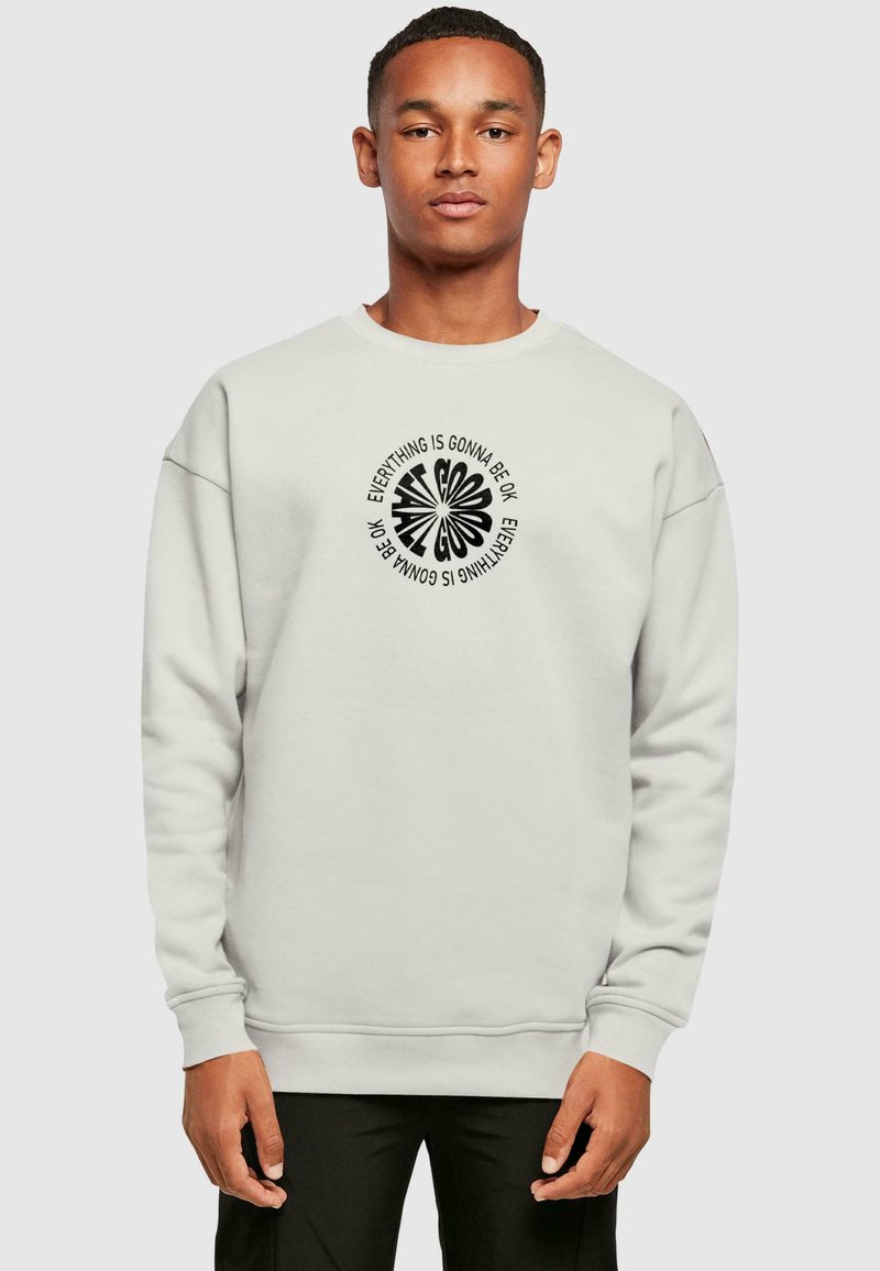 Light gray sweatshirt made of cotton blend with ribbed cuffs and hem. Central graphic features bold black text in circular design.