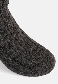Calcetín de lana gris con textura acanalada, punta redondeada y apariencia ligeramente borrosa. El material es grueso y cálido, adecuado para el clima frío.