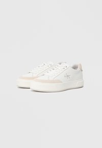 Λευκό sneaker με μπεζ λεπτομέρειες, κατασκευασμένο από υλικό με υφή. Διαθέτει στρογγυλή μύτη, επίπεδες κορδόνες και ανυψωμένη καουτσούκ σόλα. Περιλαμβάνει το λογότυπο Calvin Klein.