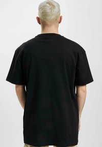 Sort bomuld t-shirt med afslappet pasform, der har korte ærmer og rund hals. Glat tekstur, minimalistisk design, ingen synlige mønstre.