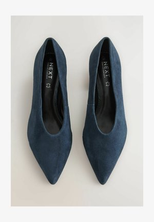 Tamsiai mėlynos iš zomšos pagamintos smailianosės bateliai su lygia tekstūra ir minimalistiniu dizainu. Vidinis pamušalas pasižymi kontrastine juoda spalva.