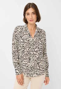 Beige langslavend shirt met een zwart luipaardpatroon, voorzien van een kraag, knoopsluiting en een relaxte pasvorm. Lichtgewicht stoftextuur.