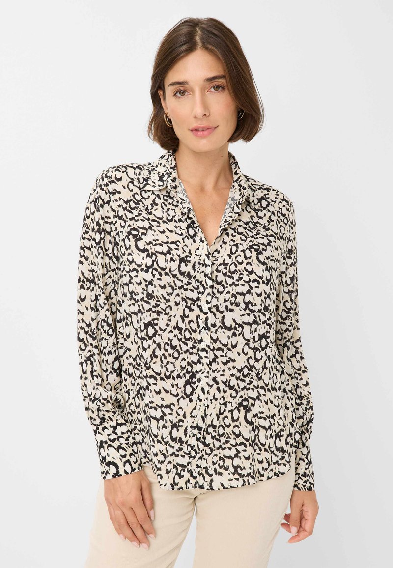 Beige langslavend shirt met een zwart luipaardpatroon, voorzien van een kraag, knoopsluiting en een relaxte pasvorm. Lichtgewicht stoftextuur.