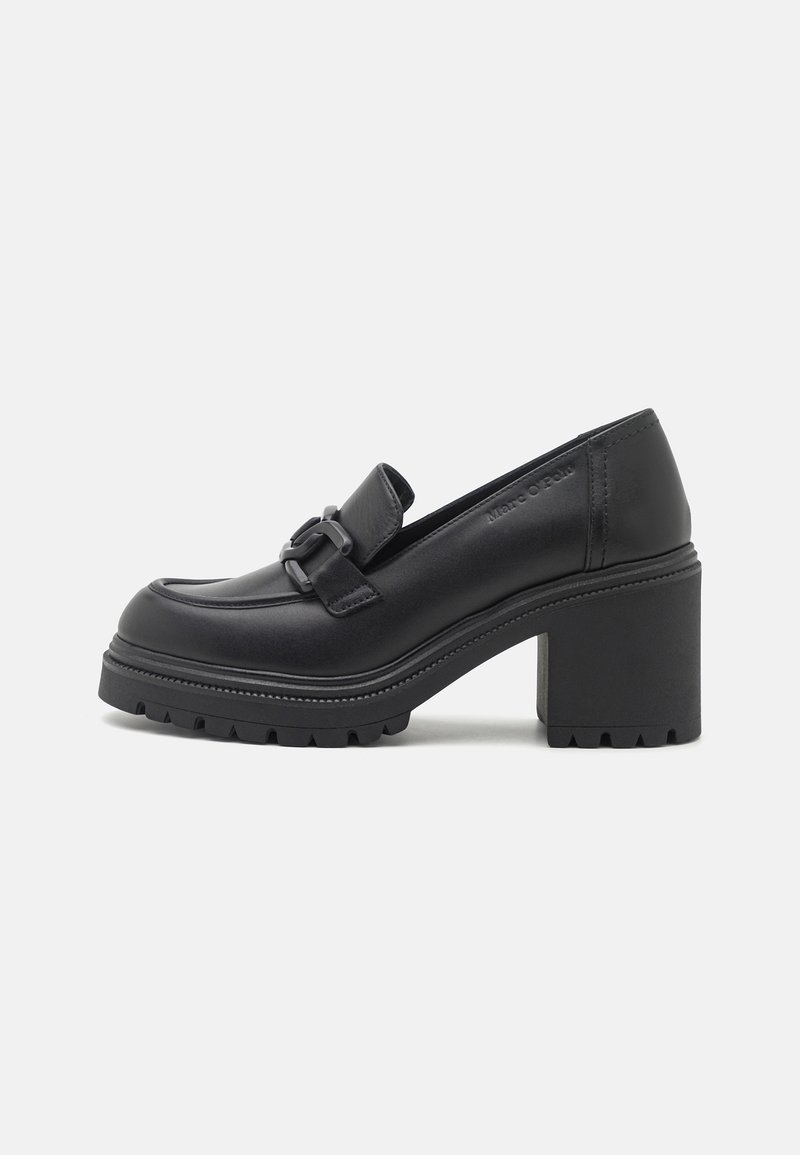 Mocassin en cuir noir à talon épais, semelle crantée et détail de boucle décorative sur la partie supérieure, vue de côté sur fond uni.