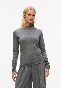 Gray knitted sweater with a high neckline and long sleeves, featuring a subtle logo detail at the chest. Soft texture and fitted design.