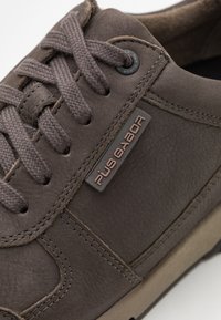 Braune Leder-Sneakers mit abgerundetem Zehenbereich, strukturiertem Obermaterial und Schnürdesign; verfügen über ein Logopatch und eine robuste Gummisohle.