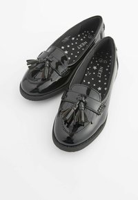 Czarne lakierowane buty skórzane z frędzlami, płaski design, okrągły czubek i kontrastowe, teksturowane wykończenie z białymi gwiazdami.