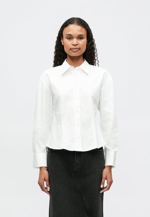 White button-up shirt with a fitted waist, long sleeves, and a collar, paired with a black denim skirt. Smooth texture, minimalistic design.