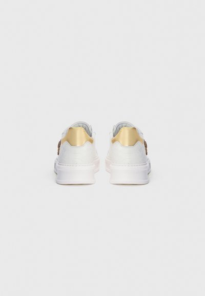 Sneakers bianchi con materiale texturizzato, dettagli dorati sul tallone e una suola intermedia liscia. Design semplice con dettagli minimi.