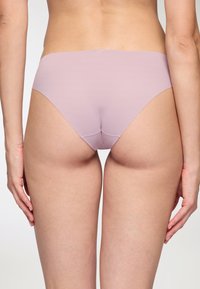 Slip in cotone lilla chiaro con una consistenza liscia e elastica, design a vita bassa e dettagli di cucitura minimalisti, visto da dietro.