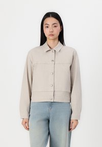 Veste courte beige clair avec des rayures verticales, fermeture à boutons et un col. Elle dispose de manches longues et d'une texture de tissu douce.