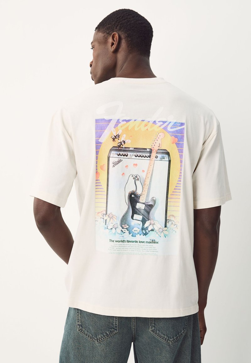 Cream-colored t-shirt featuring a colorful graphic of an amplifier and guitar with floral accents and playful penguin illustrations on the back.