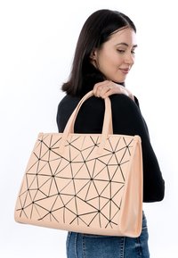 Borsa a spalla geometrica beige con motivo triangolare nero, materiale sintetico, doppi manici, forma strutturata e accenti a contrasto.