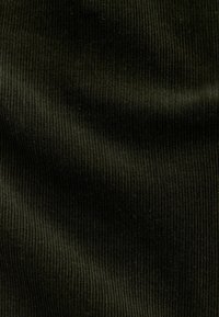 Donkergroene corduroy stof met een zachte textuur, gekenmerkt door prominente verticale ribbels en een gladde afwerking.