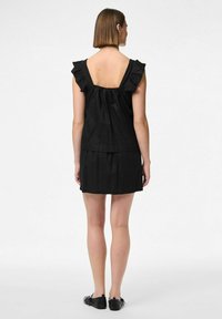 Abito nero senza maniche con scollatura arricciata, corpetto aderente e gonna fluida. Il retro è a scollo profondo con un dettaglio arricciato.