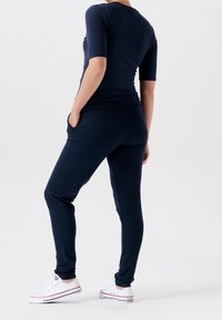 Donkerblauwe fitted top met korte mouwen en een ronde hals, gecombineerd met bijpassende taps toelopende broek met zijzakken en een elastische tailleband.