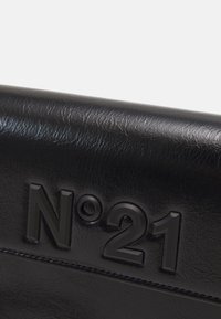 Czarna skórzana torba z wytłoczonym logo "N°21". Gładka tekstura z delikatnym połyskiem. Minimalistyczny design, podkreślający logo jako punkt centralny.