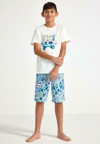 Korte mouwen crème T-shirt met de tekst "GAME ZONE" en een blauwe gamecontroller grafiek, gecombineerd met blauwe pyjamashorts met gaming-thema prints.