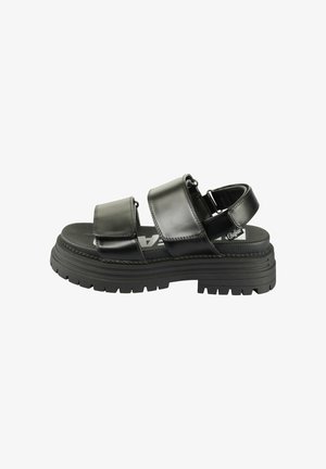 Black platform sandals with glossy leather straps, featuring two adjustable buckle closures and a textured rubber sole.