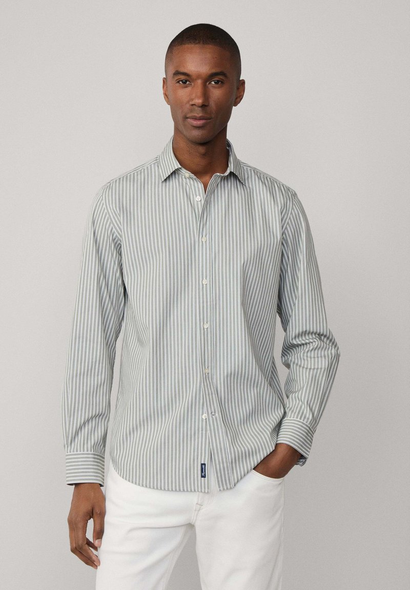 Camicia a righe in verde chiaro e bianco, realizzata in cotone. Presenta un colletto, maniche lunghe e un orlo curvo con etichetta del logo.