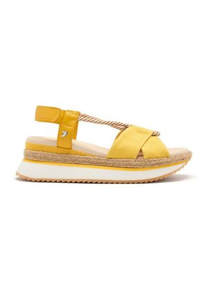 Sandalias de cuña amarillas con tiras de tela entrelazadas, suela estilo espadrille y una plantilla blanca. Detalles de cuerda texturada en la tira.