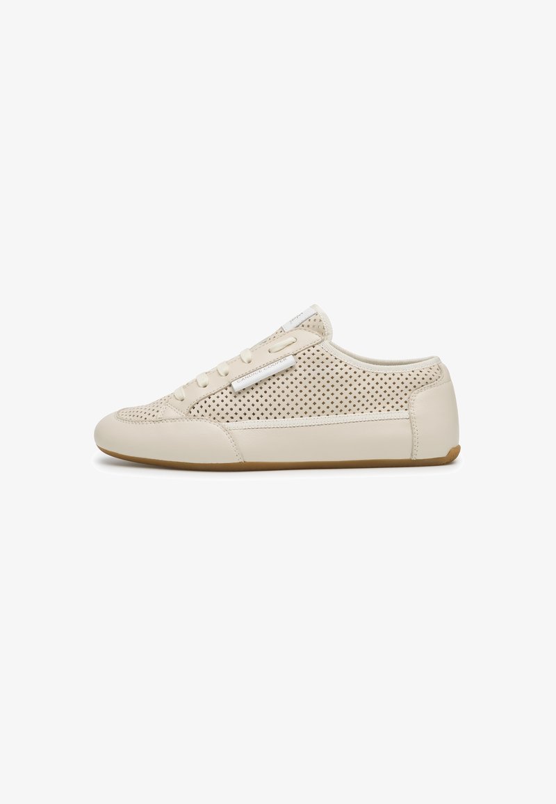 Sneaker beige slip-on con lati traforati, lacci, punta arrotondata, suola morbida e una piccola etichetta bianca del marchio sul lato superiore.