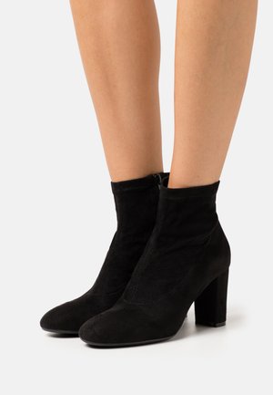 Černé semišové kotníkové boty se čtveratou špičkou a blokovým podpatkem. Zipové zapínání na boku, měkká textura a štíhlý, přiléhavý design.
