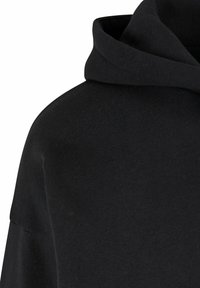 Felpa nera con cappuccio, caratterizzata da un tessuto morbido e testurizzato, vestibilità comoda e scollatura ampia. Il materiale appare liscio e informale.