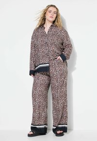 Pyjamasset i leopardmönster med en knapp-up skjorta med svarta detaljer och löst sittande byxor med randiga accenter vid fållen. Mjuk tygtextur.