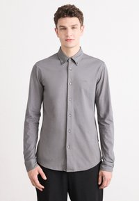 Grijze lange mouwen button-up shirt, met een klassieke kraag, een gladde textuur en een subtiel logo op de borst, gecombineerd met bijpassende knopen.