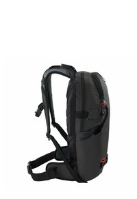 Zaino nero dal design imbottito, con spallacci regolabili, tasca laterale e cursore della cerniera rosso. Tessuto resistente con accenti texturizzati. Vista laterale.