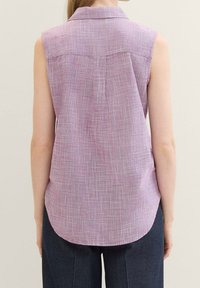 Camisa sin mangas en un patrón de cuadros de color púrpura claro con un collar, que presenta un dobladillo curvado y un detallado sutil en la parte trasera.