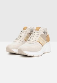 Scarpe da ginnastica beige realizzate con una combinazione di materiali in suede e mesh. Presentano un design testurizzato, dettagli dorati e una suola bianca spessa.