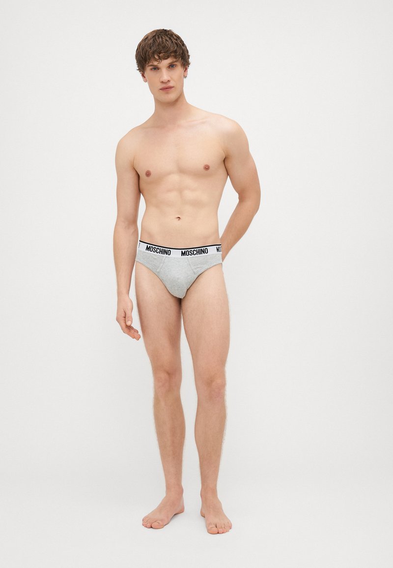 Hallid puuvillased aluspüksid musta Moschino logo vööga, millel on tihe istuvus ja minimalistlik disain, rõhutades siledat tekstuuri.