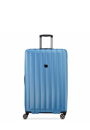 Valise rigide bleu clair avec des stries verticales, poignée rétractable et quatre roues pour une maniabilité facile.