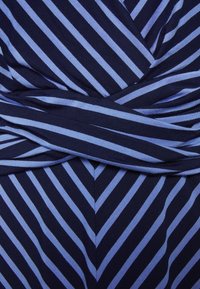 Niebieska sukienka w paseczki z krzyżującym się fasonem, z intensywnymi granatowymi i jasnoniebieskimi skośnymi paskami oraz gładką, elastyczną teksturą.