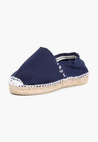 Espadrille en toile marine avec des coutures blanches, un bout arrondi et une semelle en corde de jute. Design à dos ouvert pour un enfilage facile.