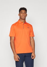 Camisa polo naranja con un patrón texturizado, de manga corta y con cuello. Presenta un acento gris alrededor del cuello y un logo en el pecho.