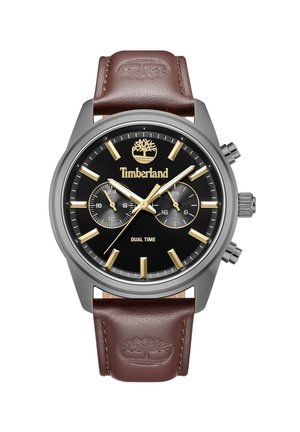 Kronograf ur med sort urskive, sølvfarvet kasse, guld time markører og en brun læderrem prægede med et logo. Har dual tidsvisning.