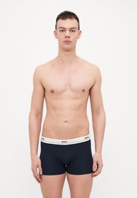Navy boxer briefs with white waistband featuring "BOSS" logo. Smooth fabric with a fitted design, minimal seams, and no visible patterns.