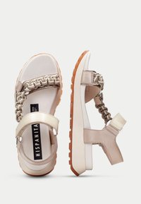 Beige sandaalit, joissa on punotuista remmeistä koostuva yläosa, sileä nahka, pehmustettu säädettävä pohja ja kumipohja, jossa on teksturoitu pito-kuvio.