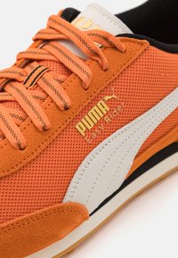 Narancssárga hálós és velúr sportcipő feh�ér PUMA csíkkal, arany logó részlettel, fekete akcentussal és struktúrált fűzőkkel. Lapos gumitalp.